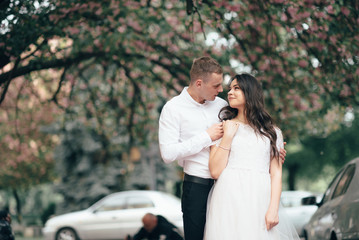 Happy young couple in love enjoys spring day, loving man holding on hands his woman carefree walking at park