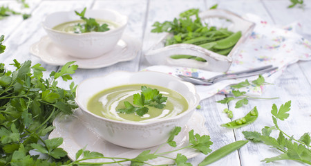 Cream soup of green peas and Parsley. Healthy lunch in a white plate on a white wooden background, Copy space,