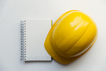 Yellow safety helmet and notebook isolated on white background. Construction and safety concept
