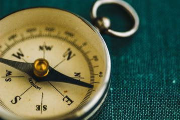 Old yellow retro compass on a green background