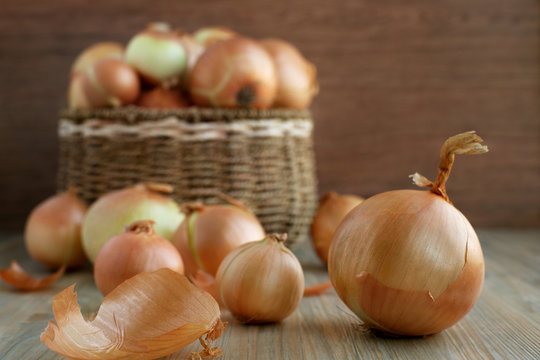 Large onions in a basket. Harvest of onions in a wicker basket on a wooden background. A lot of vegetables for a healthy diet.