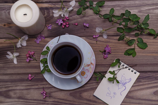 Beautiful violet lilac flowers with white cup with coffee or tea, on a wooden background
