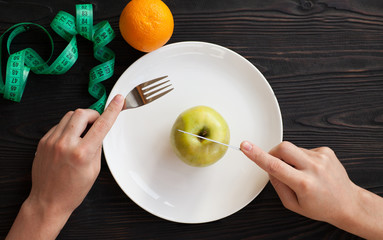 Losing weight. Strict diet. Empty plate and measuring tape instead food on wooden background top view mockup.