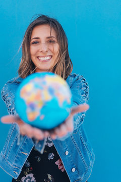 Pretty young woman offering world globe in hands