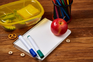 Concept of school lunch break with healthy lunch box and school supplies on wooden desk, selective focus.