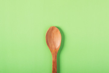 Wooden spoon on a green background in pastel color