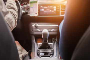 view of a gear shift and a navigator of a luxury car in a sun light. young pair is driving a vehicle. transport details concept