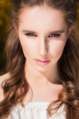 Fototapeta premium Closeup portrait of young serious woman with natural makeup in sunny day