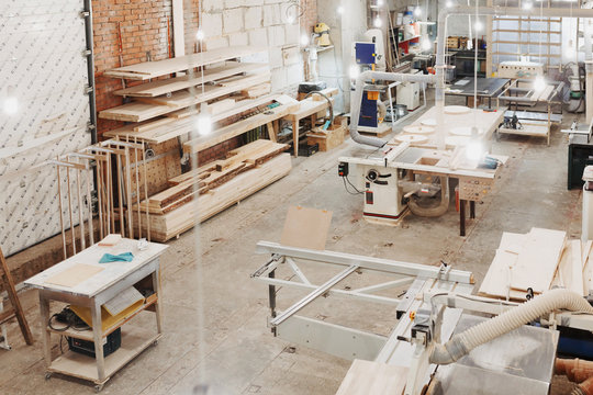 Background image of empty carpenters workshop: production equipment, various woodworking tools, wooden boards and parts of furniture in factory