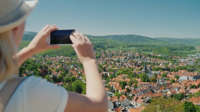Steadicam shot: A woman is holding a smartphone in her hands, photographing a beautiful view of a small German town. Holidays and travel in Europe
