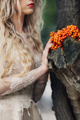 a girl in a lace dress next to a tree and a bunch of mountain ash