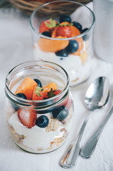 Fresh berries and fruits with natural yoghurt and granola in small glass jars. Healthy and light breakfast or snack.