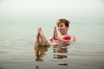 Funny girl swims in water of Dead Sea in Jordan and fog