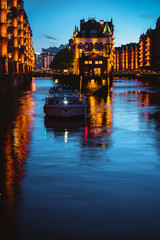 Water castle in old Speicherstadt or Warehouse district, tourist boat on a channel. Hamburg, Germany