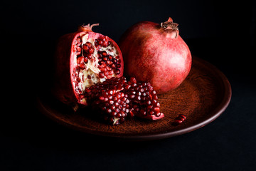 A pomegranate on a beautiful plate on the background of a dark table