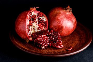 A pomegranate on a beautiful plate on the background of a dark table