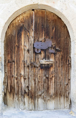 Ancient arched antique wooden doors with a metal lock in the middle