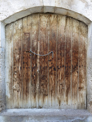 Ancient trapezoidal antique wooden doors with a metal lock in the middle
