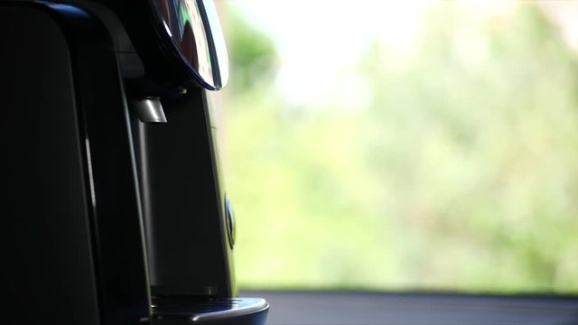 Man's hand takes a mug with a foca. Coffee streams from the coffee machine at home. Stock footage.