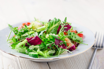 Fresh organic super food salad on white plate with fork on side