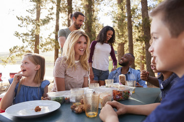 Family With Friends Camp By Lake On Hiking Adventure In Forest