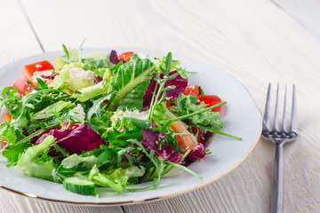 Fresh organic super food salad on white plate with fork on side