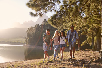 Group Of Young Friends Enjoying Walk By Lake On Hiking Adventure