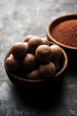 Nachni laddu or Ragi laddoo or balls made using  finger millet, sugar and ghee. It's a healthy food from India. Served in a bowl or plate with raw whole and powder. Selective focus