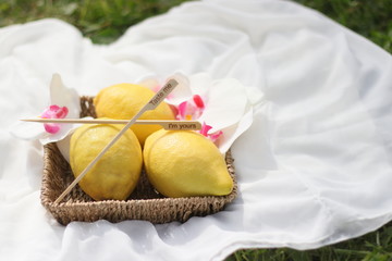 Lemons in a basket with flowers on grass