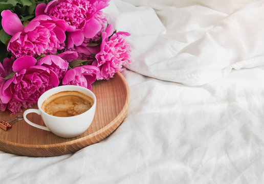 Peonies and coffee on the tray in bed.