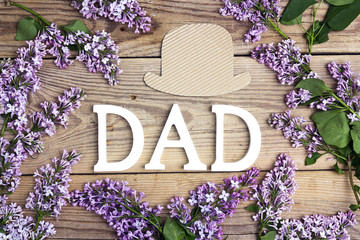 Fathers day background with letters, hat and lilac flowers on old wooden table.