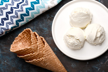 Ice cream balls, scoops and waffle cones on dark background. Advertising space.