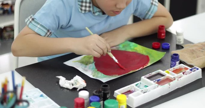 Happy asian cute child painting water colour on paper with smile face, Young boy painting decorative on a sketchpad with a brush 