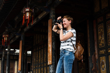 Tourist takes pictures of traditional, Chinese, wooden house
