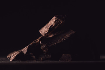 close up view of pieces of dark chocolate on black background