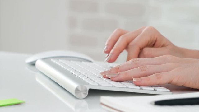 Hand of a woman typing wireless destop computer keyword on the table, dolly shot
