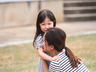 Close up happy little girl face in her mother arms.