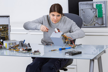 happy woman fixing computer at desk at work
