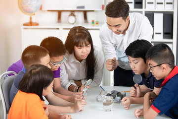 Fototapeta premium Asian teacher expanding to student in geology class with different of rock .