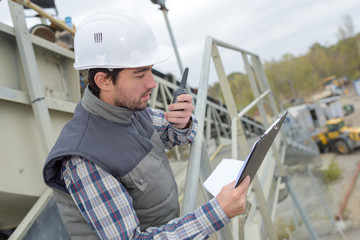 Man on construction site giving instructions on walkie talkie