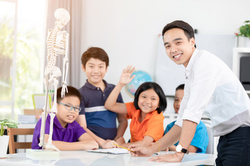 Young asian teacher ask question young kids in classroom .