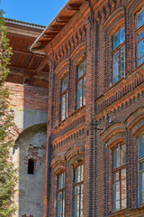 Fototapeta na wymiar Fragment of an old building of red brick, windows with wooden fr