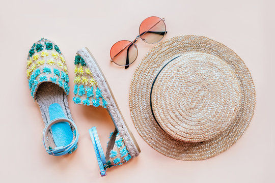 Summer fashion flatlay with espadrille sandals, gradient round sunglasses and straw hat on the beige background. Perfect beach set for holidays on the sea. Marina style.