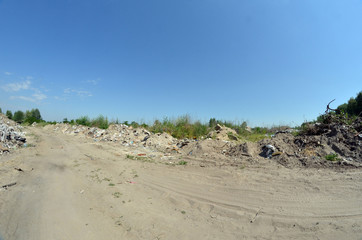Fototapeta na wymiar A rural road passes between garbage hills. Ecology of Ukraine. Nature near Ukrainian capital.Environmental contamination. Illegal junk dump. 