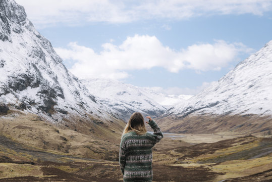 Happy Girl in knitted wool sweather dancing and enjoying a mountain view in Glen Coe, Scotland