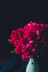 bouquet of beautiful pink peonies in vase on dark background
