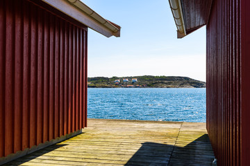 Coastal landscape seen between two wooden cabins on a pier. Ronnang on the island Tjorn, Sweden.