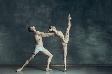 Obraz na płótnie Canvas The young modern ballet dancers posing on gray studio background
