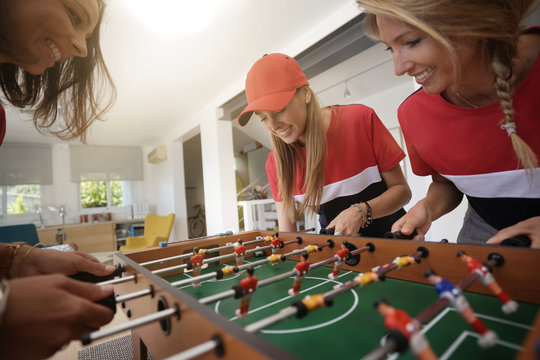 Girls having fun playing foosball at home