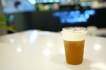 Plastic glass of iced oolong tea (wulong or wu long) with layer of cream cheese foam on blurred background and copy space, Traditional Chinese and Taiwanese Beverage. 